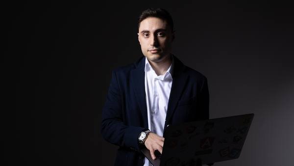 Elman Huseynov holding a laptop, studio portrait